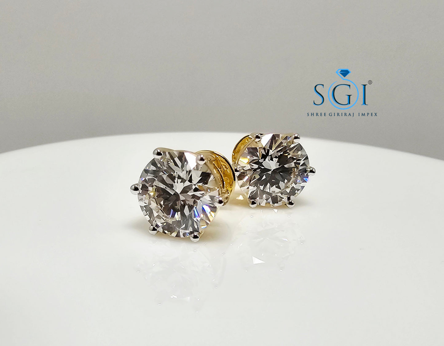 Diamond stud earrings on a white surface with SGI logo.